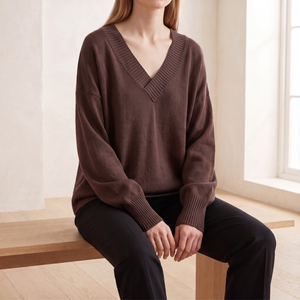 Annabel cashmere V neck sweater in Brown worn seated on a pale oak bench