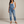Bianca denim overalls in Blue with ripped knees and rolled hems on a light gray studio backdrop