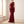 Cecily one shoulder satin maxi dress in Burgundy by a window in a bright room with plaster walls