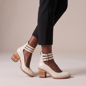 Clarisse block heel pumps in Ivory seen from the side on a light gray studio backdrop