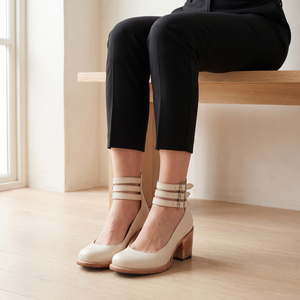 Clarisse block heel pumps in Ivory worn while seated on an oak bench