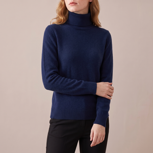 Cressida cashmere turtleneck sweater in Dark Blue on a light gray studio backdrop