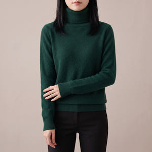 Cressida cashmere turtleneck sweater in Dark Green on a light gray studio backdrop