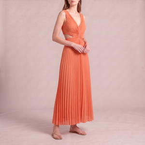 Cristina pleated maxi dress in Orange on a light gray studio backdrop