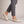 Elinor round toe flats in Ivory worn with cropped gray trousers on a light gray studio backdrop