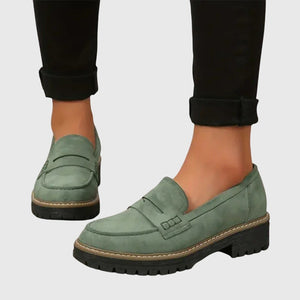 Gloria suede penny loafers in Sage worn with black cropped trousers