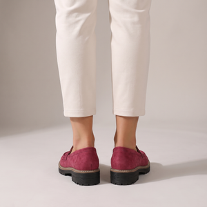 Gloria suede penny loafers in Raspberry seen from behind on a light gray studio backdrop