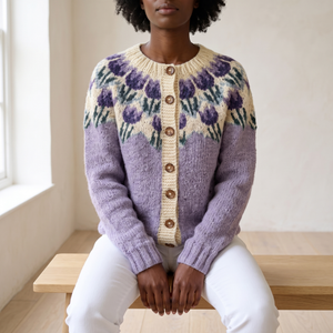 Honorine floral yoke cardigan in Lavender, seated on an oak bench