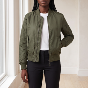 Imelda nylon bomber jacket in Olive Green worn open by a tall window in a bright room