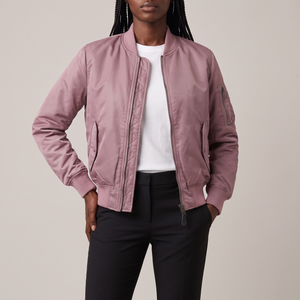 Imelda nylon bomber jacket in Pink worn open with hands at the hips on a light gray studio backdrop