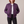 Imelda nylon bomber jacket in Purple worn open with both hands in the front pockets on a light gray studio backdrop