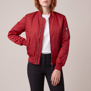 Imelda nylon bomber jacket in Red worn open with one hand on the hip on a light gray studio backdrop