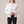 Imelda nylon bomber jacket in White worn open with hands clasped at the waist on a light gray studio backdrop