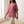 Jemima loose scoop neck blouse in Dark Pink worn loose over stone trousers, walking by a window