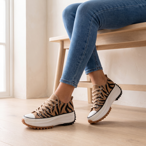 Laetitia canvas platform sneakers in Tiger Print worn while seated on an oak bench