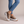 Laetitia canvas platform sneakers in Tiger Print worn with ankles crossed on a light gray studio backdrop