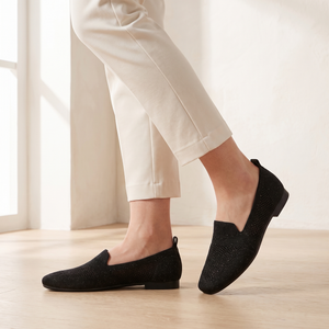 Lorelei slip on flats in Black worn by a window in a bright room