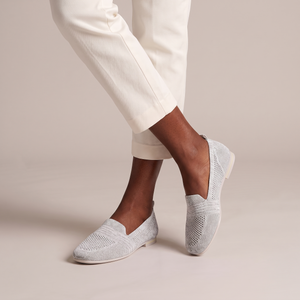 Lorelei slip on flats in Light Gray worn with ankles crossed on a light gray studio backdrop