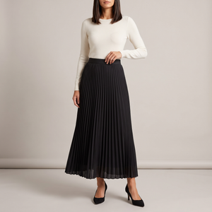 Margot pleated maxi skirt in Black with an ivory knit top on a light gray studio backdrop