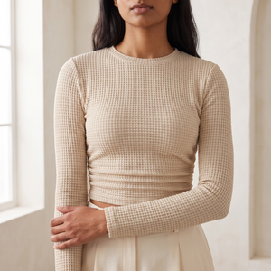 Maribel long sleeve crop top in Beige, close detail of the grid texture and gathered hem in a bright room