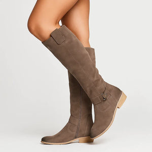 Marlene knee high suede boots in Brown with a buckle ankle strap, mid stride