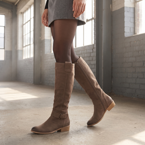 Woman walking through a sunlit warehouse in the Marlene brown suede knee high boots