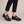 Matilda leather Mary Jane flats in Black worn with cropped black trousers on a light gray studio backdrop
