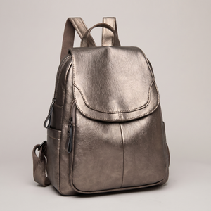 Pauline leather backpack in Bronze standing upright on a light gray studio backdrop