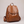 Pauline leather backpack in Cognac standing upright on a light gray studio backdrop