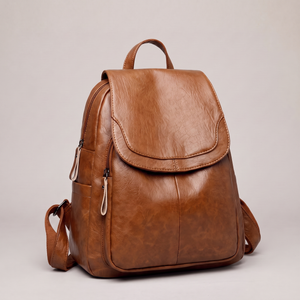 Pauline leather backpack in Cognac standing upright on a light gray studio backdrop