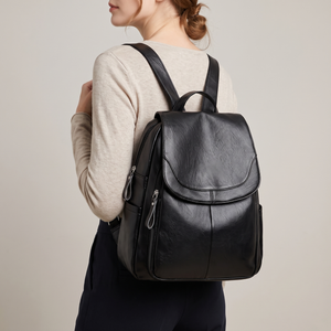 Pauline leather backpack in Black worn on both shoulders, light gray studio backdrop