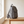 Side view of the Pauline leather backpack in Gray showing the straps, on an oak bench