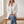 Perrine single button blazer in White, seated on an oak bench in a bright room