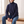 Romane chunky knit turtleneck sweater in Navy Blue worn seated on an oak bench
