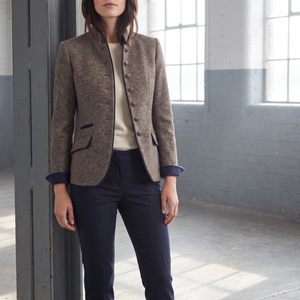 Woman in the Rosamund brown wool blazer standing beside a steel column in a sunlit warehouse