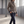 Rosamund brown wool blazer buttoned, hand in a flap pocket, walking through a warehouse