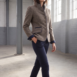 Rosamund brown wool blazer buttoned, hand in a flap pocket, walking through a warehouse