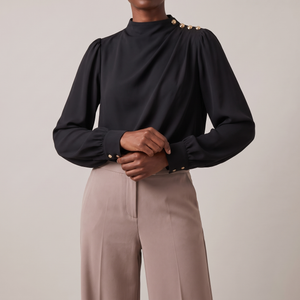 Solange draped mock neck blouse in Black on a light gray studio backdrop