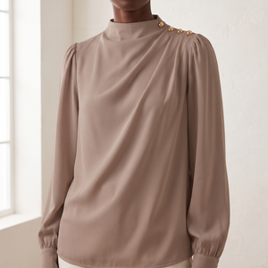 Close view of the mock neck, gold shoulder buttons and ruching on the Solange blouse in Taupe