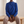 Solange draped mock neck blouse in Blue, seated on an oak bench showing the full sleeves and fitted cuffs