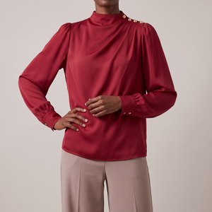Solange draped mock neck blouse in Red on a light gray studio backdrop