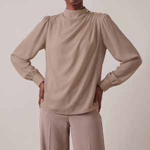 Solange draped mock neck blouse in Taupe on a light gray studio backdrop