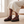 Soledad platform sandals in Burgundy worn seated on a pale oak bench