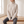 Verity lattice knit turtleneck sweater in Beige worn seated on an oak bench, showing the ribbed cuffs
